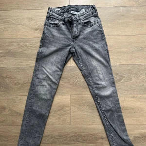Grå slim jeans från Vailent W27 L30 - Slim fit jeans i ljusgrå tvätt från Vailent. Klassisk femficksmodell med dragkedjegylf och smal passform hela vägen ner. Tillverkade i stretchig bomullsdenim för extra komfort. Perfekta för dig som gillar en clean och modern look.