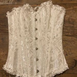 Vit korsett med mönster från Szivyshi - Säljer en vit korsett från Szivyshi köpte på amazon i storlek XS. . Har aldrig använt den, perfekt nu till Halloween!