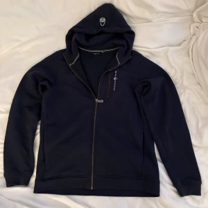 Marinblå hoodie från Sail Racing - Hoodie från Sail Racing med vit logga på bröstet och huvan, köpt på kids brandstore i storlek 176 (barnstorlek) knappt använd utan defekter