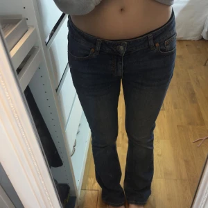 Blå bootcut jeans från Junkyard - Snygga blå jeans från junkyard med klassisk bootcut-passform. Jeansen har låg midja, fem fickor och tydliga kontrastsömmar. Materialet är robust denim i bomull och de har en lätt tvättad look framtill och baktill. Perfekta för dig som gillar en tidlös jeansstil.