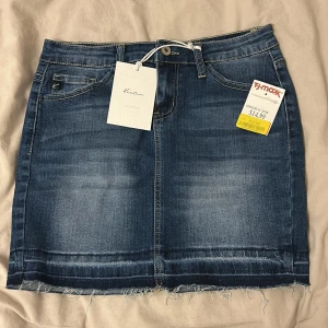 Blå jeanskjol - KanCan - Blå jeanskjol från KanCan men köpt på TJ Maxx i USA (troligtvis) med rå kant nertill och 5 fickor. Enligt Google ai är W 3/25 ”En amerikansk damstorlek som W 3/25 (midjemått 3 tum, innerbenslängd 25 tum) motsvarar ungefär en europeisk storlek 32 eller XXS och en midja på cirka 60 cm”, Anna finns det bilder på måtten