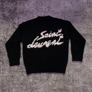 Svart Saint Laurent tröja  - Väldigt fin Saint Laurent tröja i nytt skick, svart med vit text i storlek S. Stilren och perfekt för kyligare dagar pga tröjans varma material. Hör gärna av dig vid minsta fundering om mått, pris eller annat!