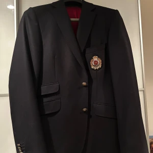 Kavaj från Morris *L* - Stilren svart kavaj från Morris med snyggt broderat emblem på bröstfickan. 