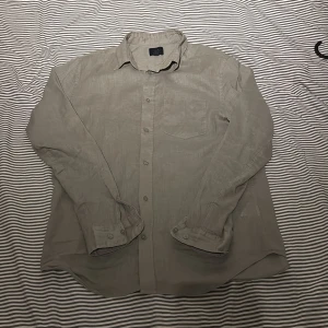 Beige linneskjorta från H&M Regular Fit - Säljer en stilren grön skjorta från H&M i regular fit. Skjortan är tillverkad i svalt linne, har klassisk krage, bröstficka och knäppning framtill. Perfekt för dig som gillar en clean och enkel look.