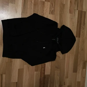 Svart hoodie från Polo Ralph Lauren - Svart hoodie från Polo Ralph Lauren i storlek S. Klassisk design med huva och snörning, dragkedja framtill och liten broderad logga på bröstet. Tillverkad i mjuk bomull, perfekt för chill dagar. Långärmad och med ribbade muddar för extra komfort.
