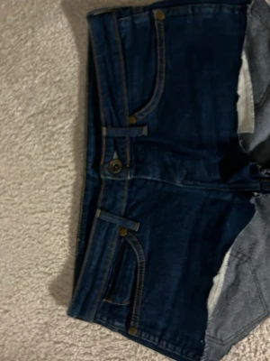 Mörkblå jeansshorts från Wrangler - Snygga mörkblå jeansshorts från Wrangler med klassiska kontrastsömmar och femficksdesign. Shortsen har hög midja, bälteshällor och tydliga bakfickor med W-detalj samt Wrangler-lapp. Perfekta för sommaren!