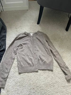 Beige kofta från H&M Basic - Säljer en enkel och stilren beige kofta den ser inte ny ut bara för att den är lite skrynklig men den är inte skrynklig i verkligheten ser bara ut så på bild den är helt ny 