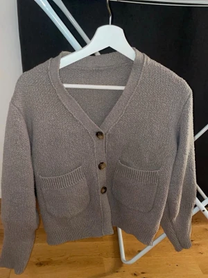 Grå kofta med fickor och knappar - Fin  grå kofta/ tröja med v-ringning och tre träknappar framtill. Två stora fickor på framsidan. Skirv för bilder på 💕