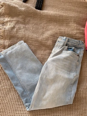 Ljusblå raka jeans från Levi's - Säljer ett par ljusblå jeans från Levi's med klassisk femficksdesign och raka ben. Jeansen har bälteshällor och knappgylf. Perfekta för en avslappnad och trendig look. Materialet är klassisk denim i bomull.