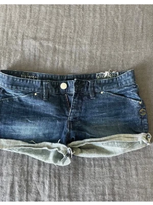 Mörkblå lågmidjade jeansshorts - Super snygga lågmidjade jeansshorts i mörkblått från Billabong. De är vintage och helt unika så finns inte att köpa längre. De är i storlek w 29 och passar perfekt på mig som vanligtvis har M/38. Populära så köp snabbt! Först till kvarn. Priset kan absolut diskuteras!