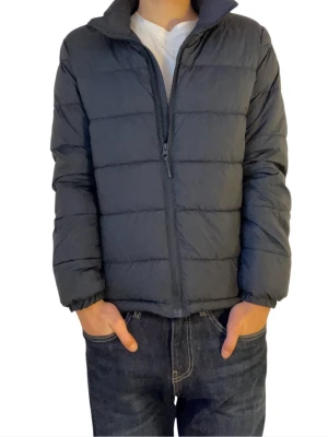 Mörkblå dunjacka med dragkedja - Snygg mörkblå dunjacka med quiltat mönster och hög krage. Jackan har dragkedja framtill och elastiska muddar vid ärmsluten. Perfekt för kalla vinterdagar och enkel att matcha med olika outfits.