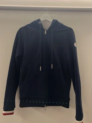 Mörkblå zip hoodie från Moncler - Säljer min mörkblåa zip hoodie från moncler, köpte från Tradera för ungefär ett år sedan och har endast använt den en gång, fås med en moncler påse till den och original lappen som sitter på den och jag kan skicka bild på det om det önskas, hoodien är storlek S och passar dig som är från 170-180cm skulle jag säga, väldigt bekväm att bära. 