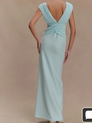 Ljusblå långklänning med djup rygg -  Isblå maxi klänning med djup v-ringning både fram och bak. Perfekt till balen eller bröllop. Helt oanvänd, endast prövad så prislapp och original förpackning finns. Finns egna bilder. 