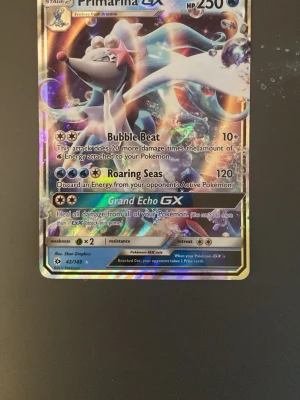 Primarina GX Pokémonkort holografiskt - Säljer ett holografiskt Primarina GX Pokémonkort med färgglad design och glansig yta. Kortet har attacker som Bubble Beat, Roaring Seas och Grand Echo GX. Perfekt för samlare eller Pokémon-fans som vill utöka sin kortsamling.