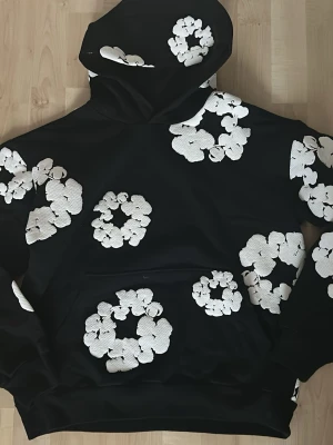 Denim tears ss25 cotton wreath sweatshirt - Säljer en original Denim Tears hoodie i storlek S. Väldigt fint skick, knappt använd och utan fläckar eller slitningar. Trycket/loggan är i toppskick och materialet är mjukt och bekvämt. TYVÄRR INGET KVITTO SPARAT!  Storlek: S Skick: Mycket bra Perfekt för streetwear/vardag. Orginalbox medföljer 