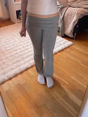 Grå foldover yogabyxor - Säljer ett par grå yogabyxor som är foldover och utsvängda ben. Byxorna är i mjukt och stretchigt material, perfekta för chill dagar hemma eller när du vill vara bekväm. Enkel och stilren design utan synliga loggor eller detaljer. Säljer eftersom de är för små för mig ❤️