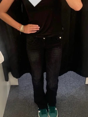 Svarta low waist bootcut jeans  - Säljer ett par svarta bootcut jeans från Gina Tricot. Använt max 5 gånger för att de var för korta på mig. (178). Jeansen har klassisk femficksdesign, knapp- och dragkedjestängning samt snygga detaljer på bakfickorna. Materialet är mjukt och stretchigt jeans-tyg för skön passform. 