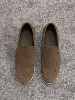 Bruna mockaloafers med vit sula - Säljer ett par stilrena loafers i brun mocka med vit sula. Aldrig använda bara testade! Skick därav skulle jag säga är 10/10.