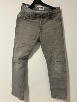 Grå jeans från Jack&Jones - Säljer ett par grå jeans från Jack&Jones i modellen CHRIS. Jeansen är i storlek W29 L32. Jeansen varsamt använda, men har en fläck på framsidan vid ankeln. Pris kan förhandlas. Fler bilder kan skickas vid behov.