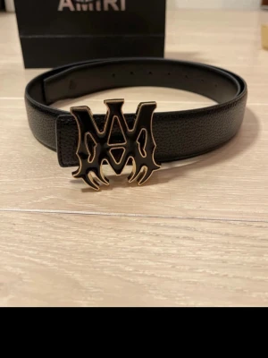 Amiri Core Logo belt - Snyggt svart bälte från Amiri i läder med ett stort, unikt metallspänne i guld med Amiri-logga. Oanvänt helt ny.