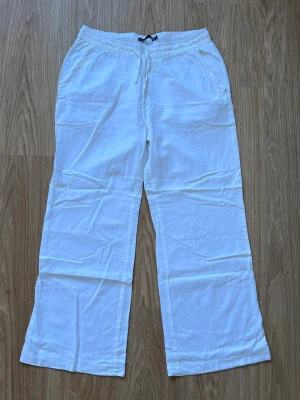 Vita linnebyxor från 157 - Ett par vita linnebyxor från Lager157 med snörning och resår i midjan. Raka ben, två sidofickor och en bakficka. Nyskick, inga tecken på användning!