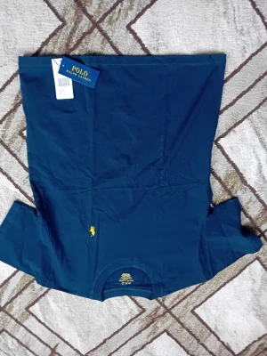 Mörkblå t-shirt från Polo Ralph Lauren - Mörkblå t-shirt från Polo Ralph Lauren med klassisk gul broderad logga på bröstet. T-shirten har rund halsringning och korta ärmar. Tillverkad i mjuk bomull för en bekväm känsla. Perfekt för en stilren och avslappnad look.