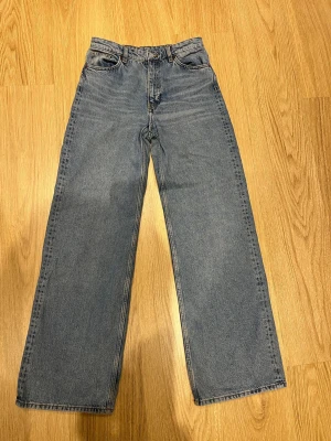Monki wide jeans W28 - Säljer ett par klassiska blå jeans med rak/wide passform och medelhög midja från Monki. Jeansen har fem fickor och stängs med knapp och dragkedja. Knappt använda och väl vårdade. 
