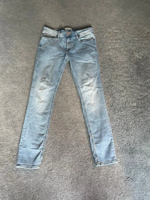Ljusblå skinny jeans Jack & Jones - Säljer ett par ljusblå skinny jeans från Jack & Jones. Jeansen har klassisk femficksmodell, dragkedjegylf och snygga slitningar framtill. Tillverkade i mjuk denim med stretch för extra komfort. Perfekta för en avslappnad och trendig look.