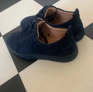  Christian Louboutin sneakers - Snygga mörkblå sneakers från Christian Louboutin i mocka med klassisk röd sula och broderad logga på hälen. . Perfekt för dig som gillar exklusiva detaljer och stilren design.Har box.