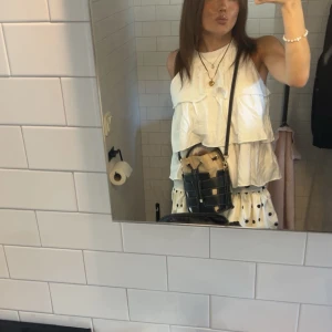 Vit volangig linnetopp - Säljer en vit halterneck med dubbla volanger och classy och sommrig design. Toppen har en luftig passform. Perfekt att matcha med kjol eller jeans för en fräsch look.