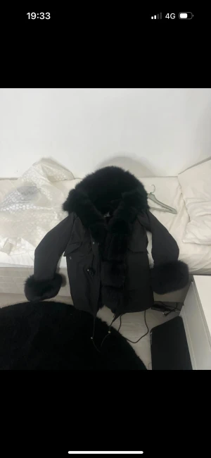 Svart parkajacka med pälsdetaljer - Säljer en svart parkajacka från Moensohoq i storlek M. Jackan har fluffiga pälsdetaljer på krage och ärmslut, samt huva och snörning i midjan. Perfekt för dig som vill ha en varm och snygg jacka med extra attityd under vintern. Aldrig använt skriv för frågor och pris