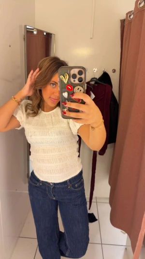 Vit ribbad blus med puffärm - Säljer en söt vit blus med ribbad struktur och korta puffärmar. Toppen har en rund halsringning och är figurnära med elastiska detaljer som ger en cool textur. Perfekt att styla med jeans eller kjol för en fräsch look. Används inte. Aldrig använd