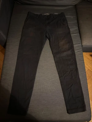 Svarta Levi's XX Chino Slim Taper W32 L32 - Svarta chinos från Levi's XX Chino med slim taper passform. Klassisk design med fickor fram och bak, bälteshällor och knappstängning. Materialet är mjukt och bekvämt, perfekt för dig som gillar stilrena och smala byxor.