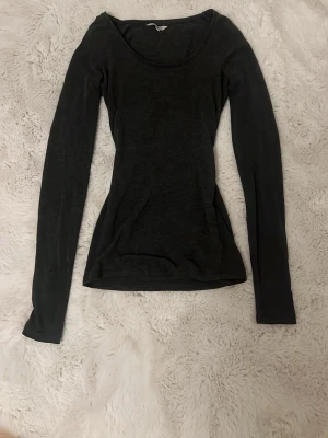 Mörkgrå långärmad topp från mbyM - En enkel och stilren mörkgrå långärmad topp från mbyM i storlek XS. Toppen har rund halsringning och är figurnära i modellen, perfekt att matcha med jeans eller kjol. Materialet känns mjukt och lätt.
