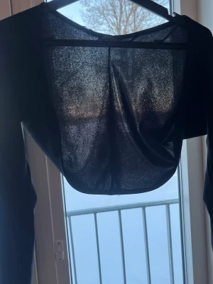 Svart mesh bolerotopp från Missäy - Säljer en svart bolerotopp från Missäy med lång ärm. Toppen är gjord i ett tunt material. Perfekt att slänga över ett linne eller klänning för extra lager och stil.