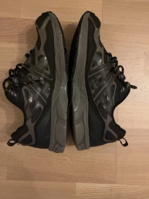 Asics Gel NYC - Säljer ett par chunky sneakers i svart och grått med coola detaljer och mönstrade snören. Skorna har en rejäl sula och dragflik bak för enkel påtagning. Perfekta för dig som gillar streetwear och vill ha en sportig look. Bild 5 är med flash, alltså har de reflex.