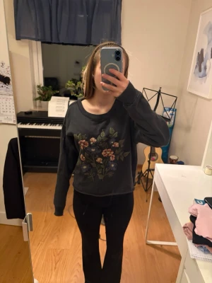 Mörkgrå sweatshirt - Superfin mörkgrå sweatshirt från Hollister med broderade blommor framtill. Tröjan har rund halsringning och långa ärmar.