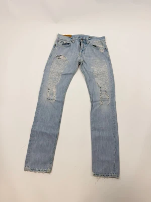 Ljusblå Dondups med slitningar - Säljer ett par ljusblå jeans från dondup och flera hål och slitningar för en riktigt edgy look. 