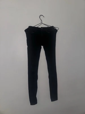 Svarta skinny jeans från Replay  - Säljer ett par svarta skinny jeans med klassisk femficksdesign och dragkedja. Jeansen har en tight passform och är tillverkade i ett stretchigt jeansmaterial som sitter snyggt längs benen. Perfekta för dig som gillar en stilren och enkel look.