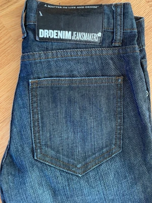 Mörkblå Dr Denim jeans skinny fit - Säljer ett par mörkblå jeans från Dr Denim med klassisk femficksdesign och skinny passform. Jeansen har normal midja och är tillverkade i ett mjukt och stretchigt denimtyg som sitter tajt längs benen. Perfekta för dig som gillar en smal siluett. 24/32