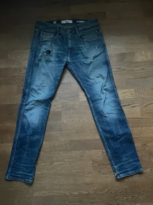 Replay Anbass Slim Fit Jeans Blå 33 - Säljer ett par Replay Anbass slim fit jeans i klassisk blå tvätt. Jeansen har slitningar, hål på låret och snygga detaljer på bakfickorna. De är raka i modellen och har en modern, smal passform. Perfekta för dig som gillar en avslappnad men trendig look. priset är ej hugget i sten, vid övriga frågor och funderingar är det bara att skriva🙌🏻
