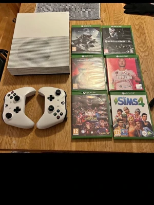 Xbox One S med två handkontroller och 6 spel - Xbox One S i vitt med två trådlösa handkontroller. Inkluderar 6 populära spel: Destiny, Mortal Kombat XL, Tekken 7, FIFA 20, Marvel vs Capcom Infinite och The Sims 4, och även watch dogs 2 finns. Konsolen och tillbehören ser ut att vara i gott skick utan synliga skador.