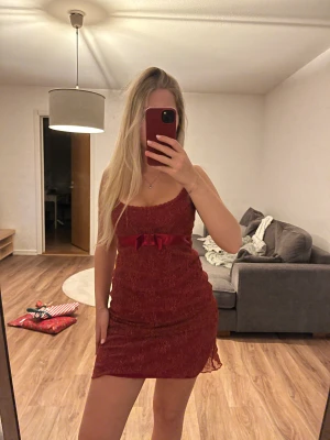 Röd klänning  - Röd glittrig klänning med rosett, går att ha så kort man vill, andra bilden är riktiga längden. 