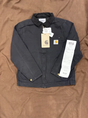 Svart Carhartt jacka S - Svart Carhartt jacka som är helt oanvänd. Köpt på SNS i våras men glömde helt att använda den så för helst tillbaka en del av pengarna så man kan droppa på lite annat. Riktigt skönt starkt material med skön insida. Carhartts klassiska tjocka dragkedja och guldknappar. Sitter riktigt bra på modellen som är 179 65kg. Skickar eller möts i Stockholm. 