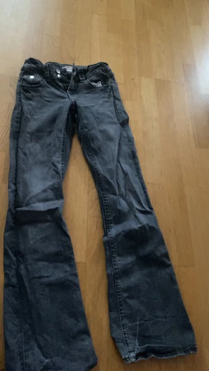 Svarta bootcut jeans från Gina Tricot - Snygga svarta jeans från Gina Tricot i storlek 158. Modellen har klassisk femficksdesign, silverfärgade knappar och en bootcut passform som ger en schysst siluett. Jeansen är tillverkade i jeansmaterial och har en mörk tvätt.