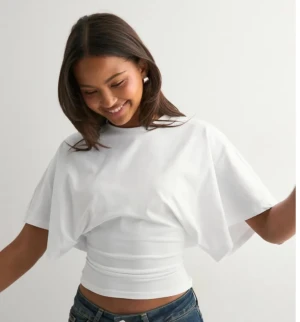 Vit croppad topp med vida ärmar - Säljer en vit croppad topp med breda, korta ärmar och rund hals. Toppen har en tight passform över midjan. Säljer då jag inte använder den. Helt ny 