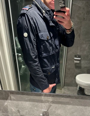 Mörkblå fieldjacket från Snoot  - Säljer en riktigt schysst field jacket från Snoot. Jackan är i riktigt bra skick men tyvärr för liten på mig. Jag på bilden är 188cm. Hör av er vid frågor:)