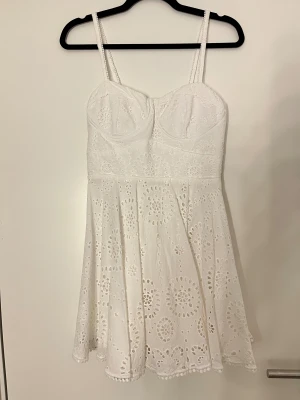 Vit kort klänning med broderade detaljer - Superfin vit kort klänning med smala axelband och broderade blommönster. 