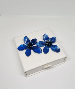 Blå blommiga örhängen i resin - Unika örhängen formade som blommor i intensivt blått resin med glansig finish. Varje blomma har fem kronblad och en detaljrik svart och blå spiral i mitten. Perfekt för dig som vill sticka ut med färg och cool design.