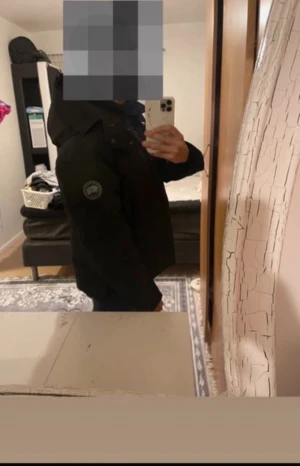 Svart dunjacka från Canada Goose - Svart dunjacka från Canada Goose med huva och klassisk logotyp på ärmen. Jackan har en stilren look med knappar framtill och långärmade ärmar. Perfekt för kalla dagar och har en normal passform. Materialet är slitstarkt och isolerande.